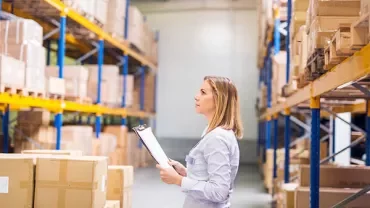 Person with clipboard checking boxes in a warehouse.