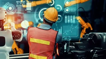 Robots and worker interact with digital interface in futuristic factory.