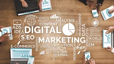 People using tablets at a table with digital marketing words.