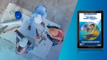 Construction workers reviewing plans at a site with a hiring guide on a tablet.