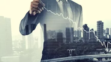 Person drawing declining graph over cityscape.