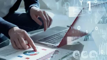 Person working on a laptop, analyzing charts and graphs.