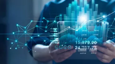 Person holding a tablet with digital graphs and data overlay.