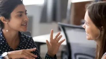 Two people engaging in a lively discussion at an office setting.