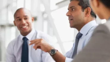 Three people engaged in discussion at a business meeting.