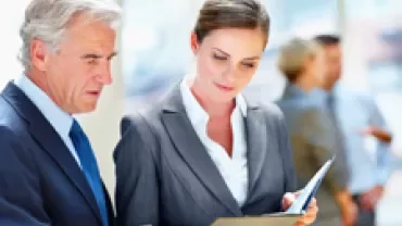 Two people in business attire reviewing a document in an office setting.