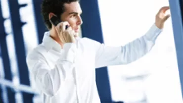 Person in white shirt talking on a phone by a window.