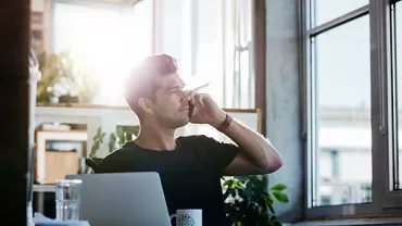 Person talking on a smartphone in a sunlit office.
