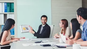 Business meeting with people discussing a pie chart.