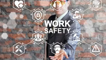 Person in suit and hard hat with work safety icons on screen.