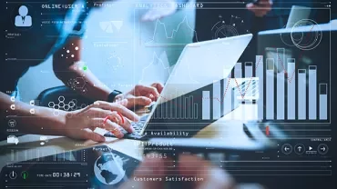 Hands typing on a laptop with digital analytics graphics overlays.